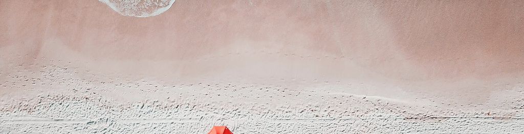 A stretch of sand with a wavy line of footprints marked across it from left to right.