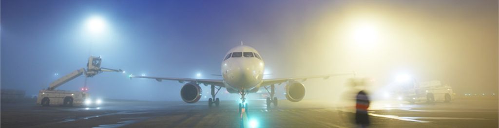 Maintenance crew de-ices a plane at night.