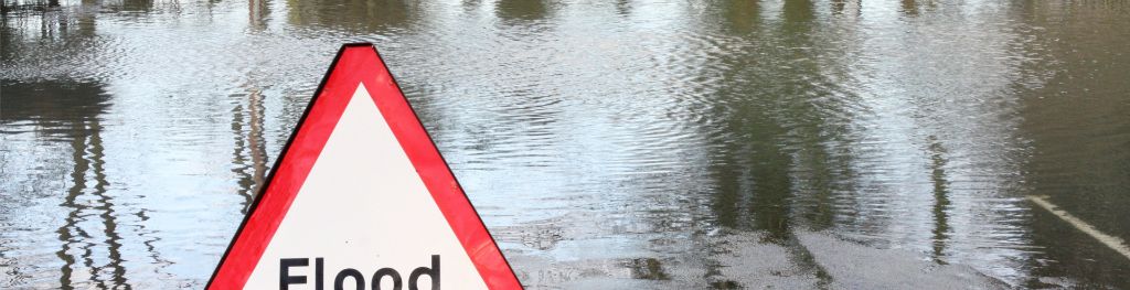 A flood warning sign erected on a water-logged road