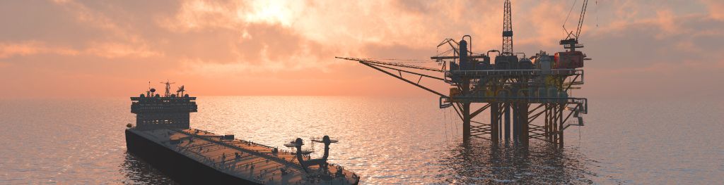 An oil tanker approaches an oil platform in the sunset