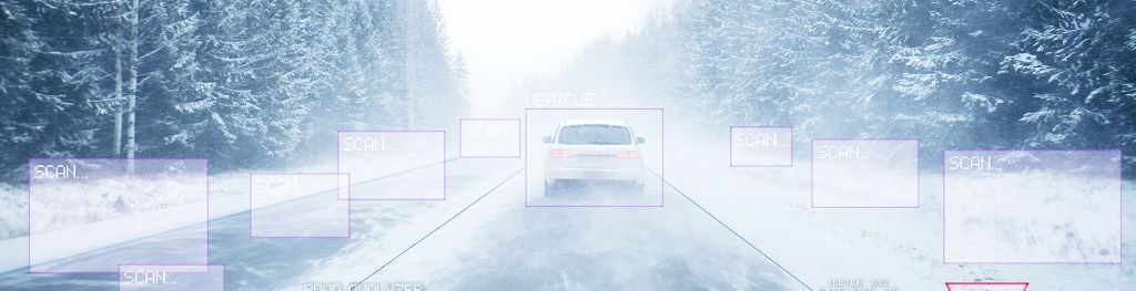 A car in motion in snowy and foggy conditions, viewed from a Connected and Autonomous Vehicle digital system displaying real-time weather data and a road surface analyser.