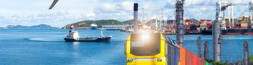 Rail freight containers against a backdrop of a cargo ship entering a port and a commercial aircraft flying overhead.