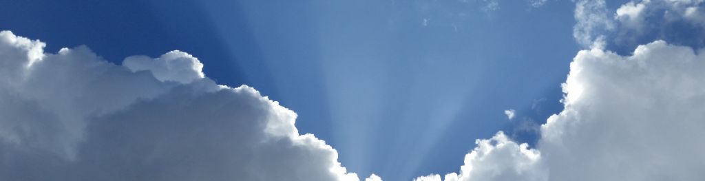 Crepuscular rays passing through clouds against a blue sky.