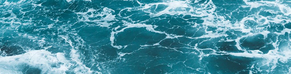 A blue-green ocean surface with waves and sea foam.