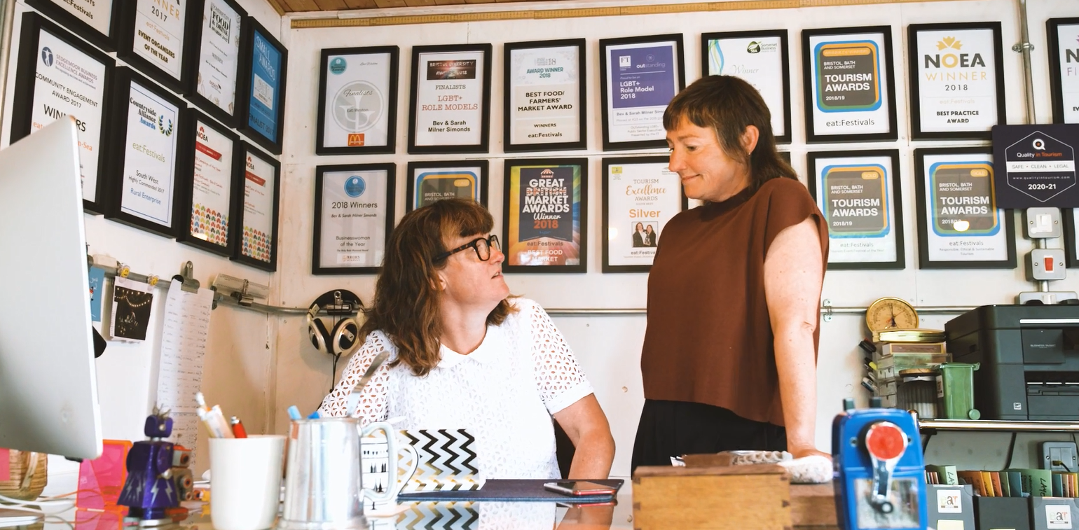 Bev and Sarah, Founders of eat:Festivals, looking at each other behind a desk