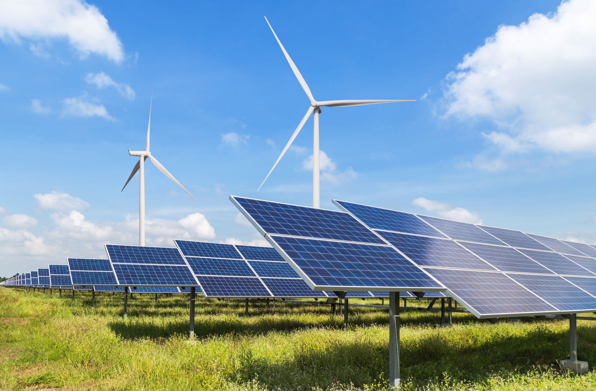 Solar panels on field and wind turbines in background.